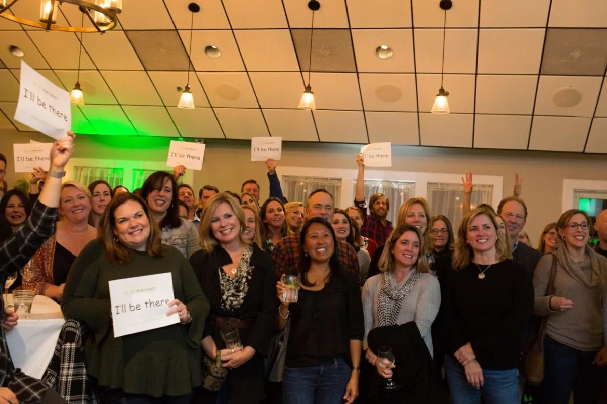 A sold-out crowd of more than 130 community members from Merrimac, Groveland and West Newbury hold up signs pledging "I'll Be There" on voting day. They filled Michael's Harborside in Newburyport at the We Are Pentucket campaign kickoff party on Oct. 25, 2018. (Courtesy Photo)