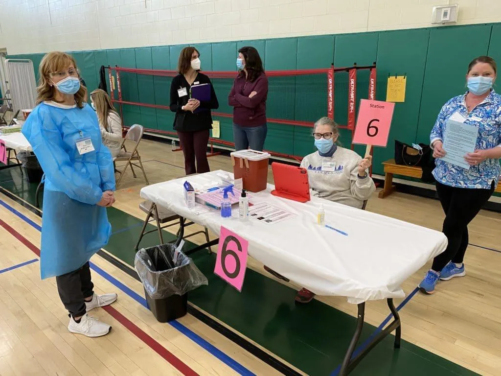 Ann Brady-Lozier (far left), school nurse at the Dr. Frederick N. Sweetsir School in Merrimac, waits with other volunteers at one of the eight vaccination stations set up at Saturday's Lower Merrimack Valley Vaccine Clinic session in West Newbury. (Courtesy Photo)